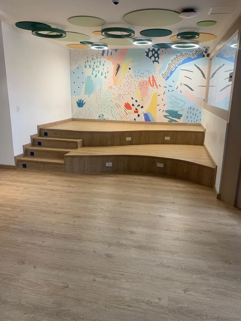 Tarima de madera con escalones en un salón con mural de colores