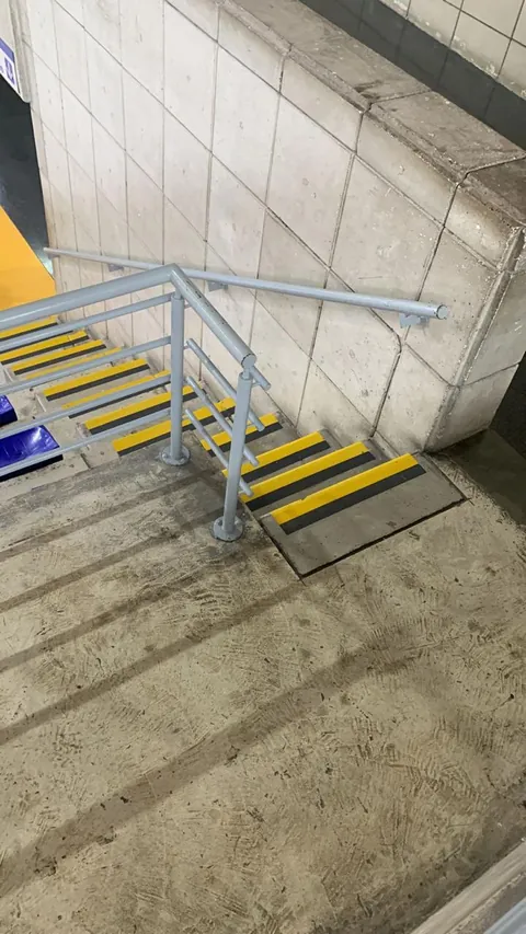 Escalera con pasamanos y baranda metálica y bordes antideslizantes amarillos