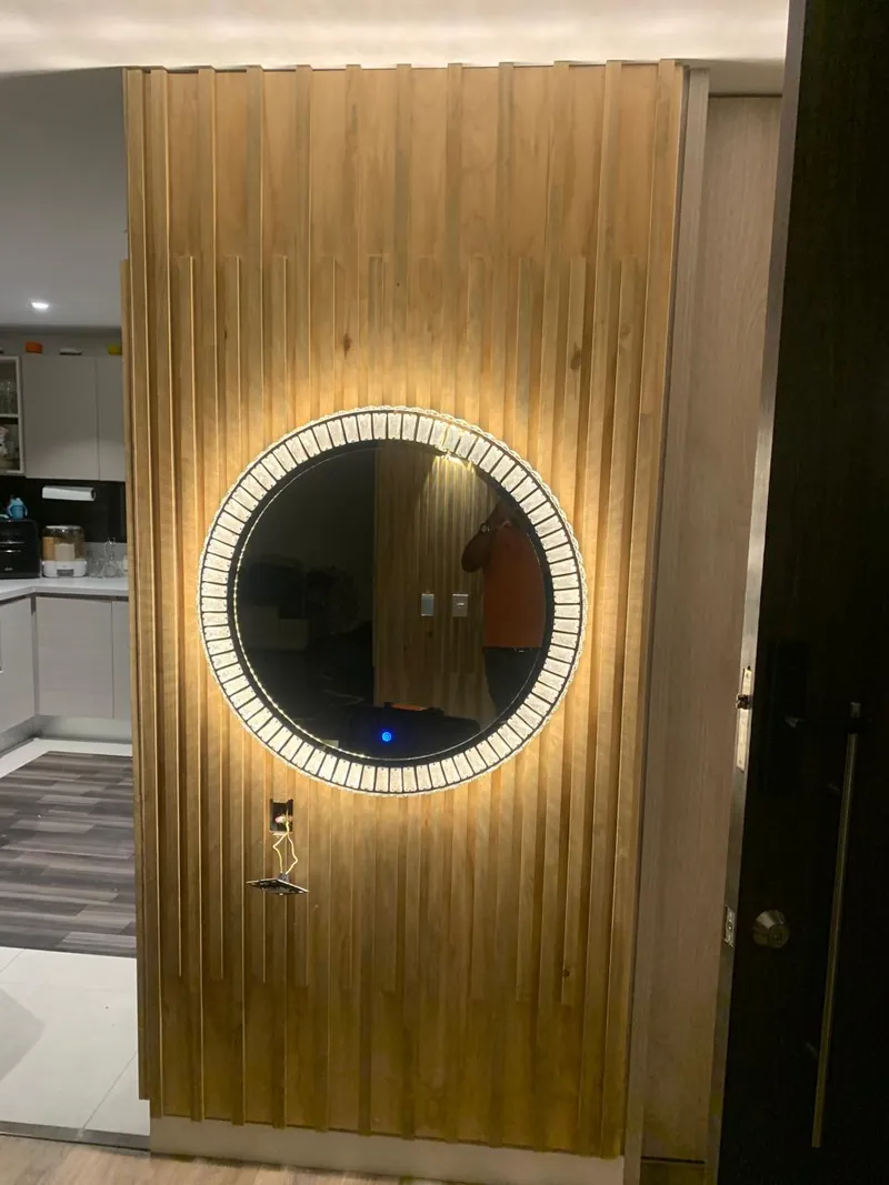 Panel decorativo de listones de madera con espejo redondo con borde iluminado