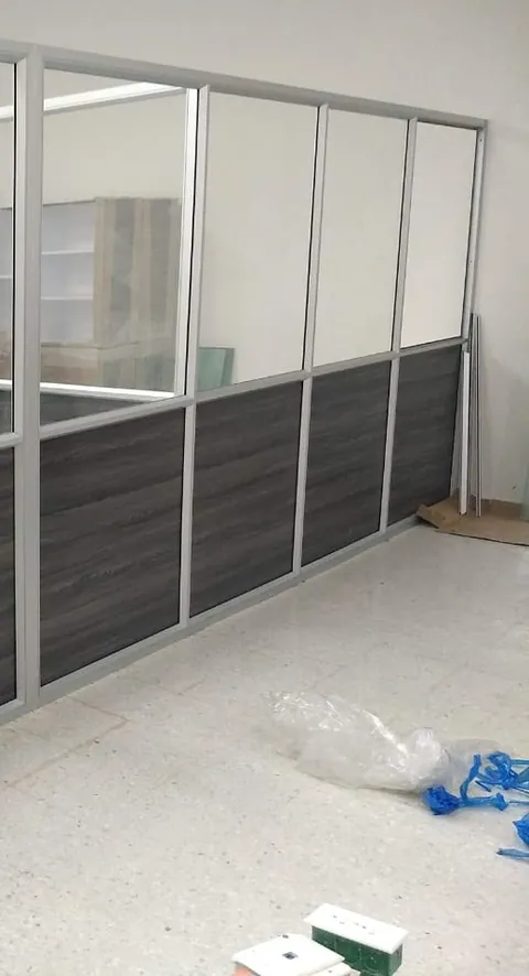 División de oficina en perfilería de aluminio y vidrio con zócalo en tablero tono grafito