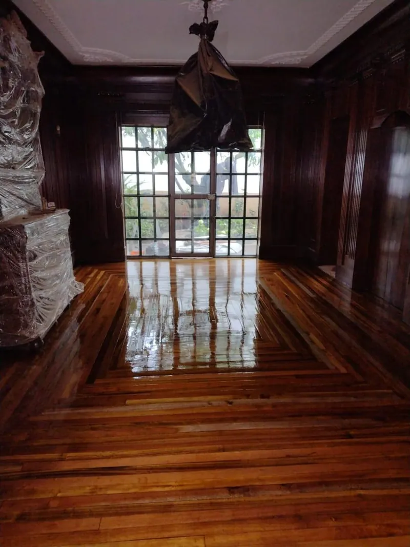 Habitación revestida en paneles de madera oscura con piso de parqué brillante