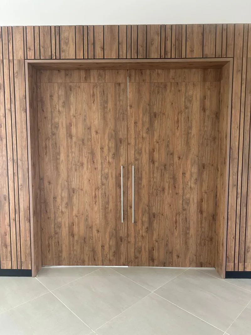 Puerta doble batiente de madera sobre un muro revestido en listones, fabricados por IPM